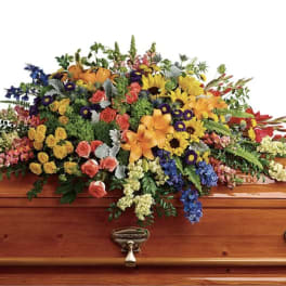 Colorful floral casket spray on a wooden coffin