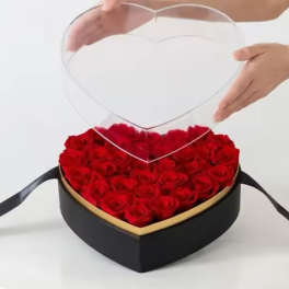 Heart-shaped box filled with red roses and a clear heart topper