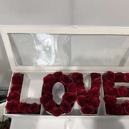 Red roses arranged in a white box to spell "LOVE".