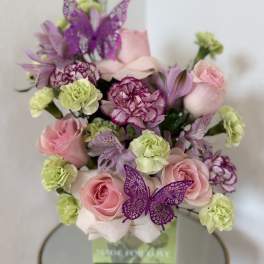 Pink roses and purple carnations in a box with butterfly decorations