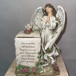 Angel figurine beside a memorial box decorated with pink roses