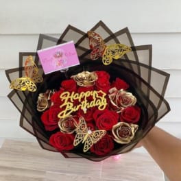 Bouquet of red and gold roses with butterfly decorations and a birthday sign