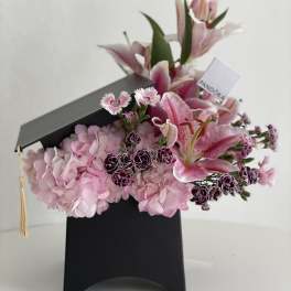 Pink lilies and hydrangeas arranged in a black graduation box