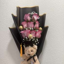 Pink rose bouquet with a teddy bear and graduation ribbon