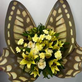 Yellow lilies and white roses arranged with butterfly wings behind them