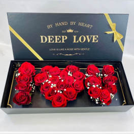 Red roses arranged in a heart-shaped gift box with a ribbon