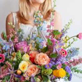 Woman holding a large mixed bouquet in a glass vase