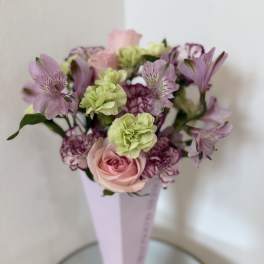 Pink and purple bouquet in a tall pale vase