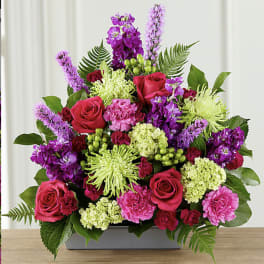 Bright pink and purple floral arrangement in a rectangular vase