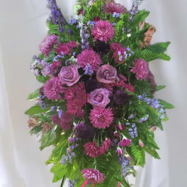 Tall standing spray of purple roses and pink mums arranged in a cascading shape on an easel.