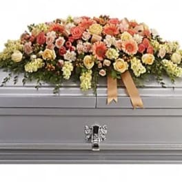 Floral casket spray with peach, pink, and cream flowers