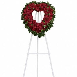 Heart-shaped standing wreath of red roses on a white easel