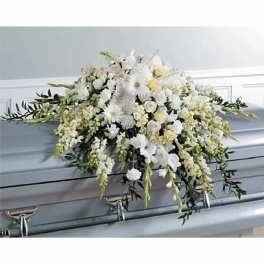 White floral casket spray with cascading greenery on a gray casket