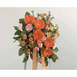 Orange gerbera daisy arrangement with pink accents on a stand