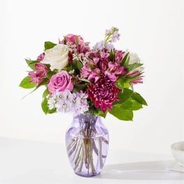 Pink and white mixed bouquet in a purple glass vase