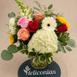 Mixed bouquet of roses, gerbera daisies, and hydrangea in a glass vase