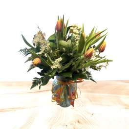 Bouquet of orange tulips and white filler flowers in a glass vase