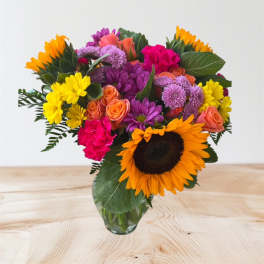 Mixed bouquet with sunflowers, roses, and chrysanthemums in a glass vase
