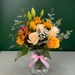 Bouquet of yellow and cream roses with orange flowers in a glass vase