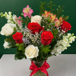 Bouquet of red and white roses with pink alstroemeria in a glass vase