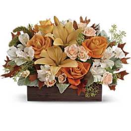 Orange roses and lilies arranged in a wooden box
