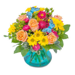 Peach roses and yellow daisies in a blue glass vase with butterfly picks