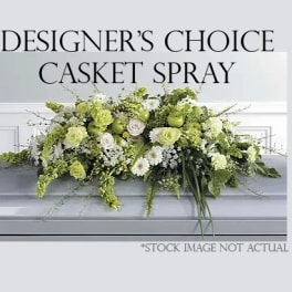 Green and white casket spray with mixed flowers on a gray casket