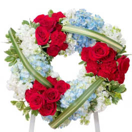 Heart-shaped floral wreath with red roses, blue hydrangeas, and white flowers