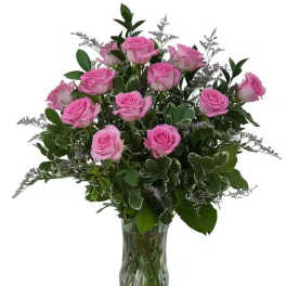 Pink roses arranged in a clear glass vase with greenery