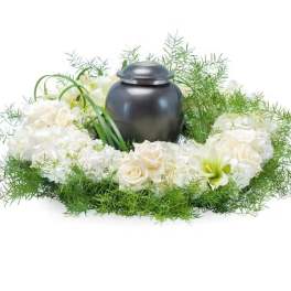 White floral wreath around a dark urn-shaped container