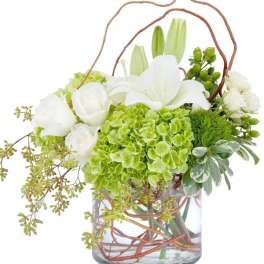 White lilies and green hydrangeas in a glass vase with curly branches