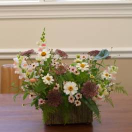 Mixed bouquet of white and pink flowers in a rustic wooden container