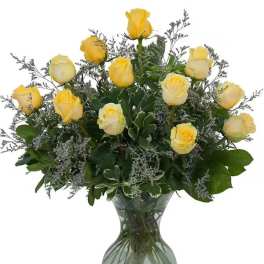 Yellow roses arranged in a clear glass vase with greenery