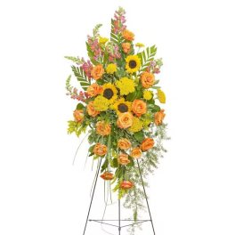Tall floral standing spray with orange roses and yellow sunflowers on a metal easel