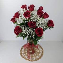 Red roses arranged in a clear glass vase with white baby's breath
