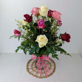 Bouquet of multicolored roses in a clear vase with a pink ribbon