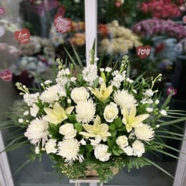 White floral arrangement in a wicker basket on a stand