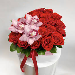 Red roses with pink orchids in a white box tied with a red ribbon