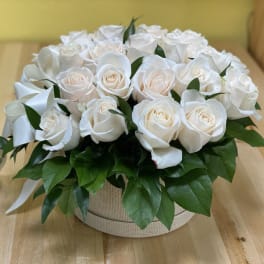 Round arrangement of white roses in a beige box with a white ribbon