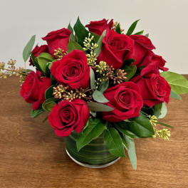 Red roses arranged in a green glass vase