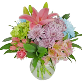 Pink lilies and mixed pastel flowers in a clear glass vase