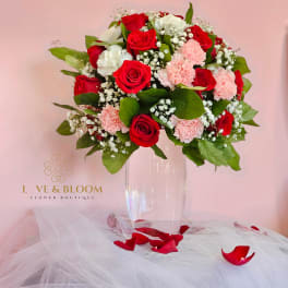 Red and pink rose bouquet in a clear vase with white filler flowers