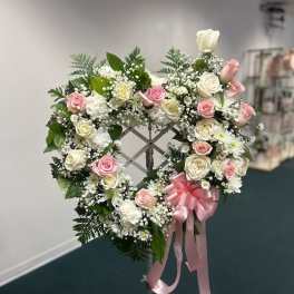 Heart-shaped wreath of pink and white roses with a pink ribbon