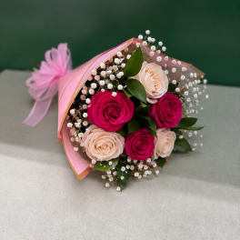 Bouquet of pink and blush roses with baby's breath wrapped in pink paper