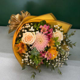 Bouquet of peach and pink flowers wrapped in gold paper