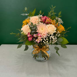 Mixed bouquet of roses, daisies, and pink flowers in a glass vase
