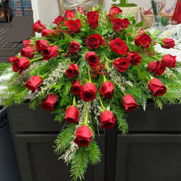 Cascade of red roses with evergreen accents on a dark table