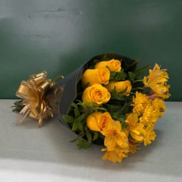 Yellow roses and yellow flowers wrapped in black paper with a gold bow
