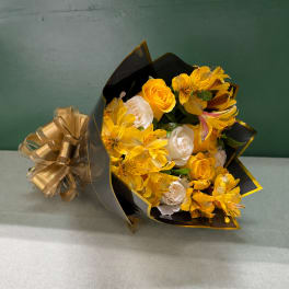 Yellow and white bouquet wrapped in black paper with a gold ribbon