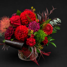 Red and magenta mixed flower arrangement in a clear glass vase